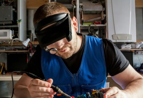 Bild zeigt Mann beim reparieren eines elektronischen Geräts mit einem Lötkolben. Foto: (c) Bermix Studio auf Unsplash