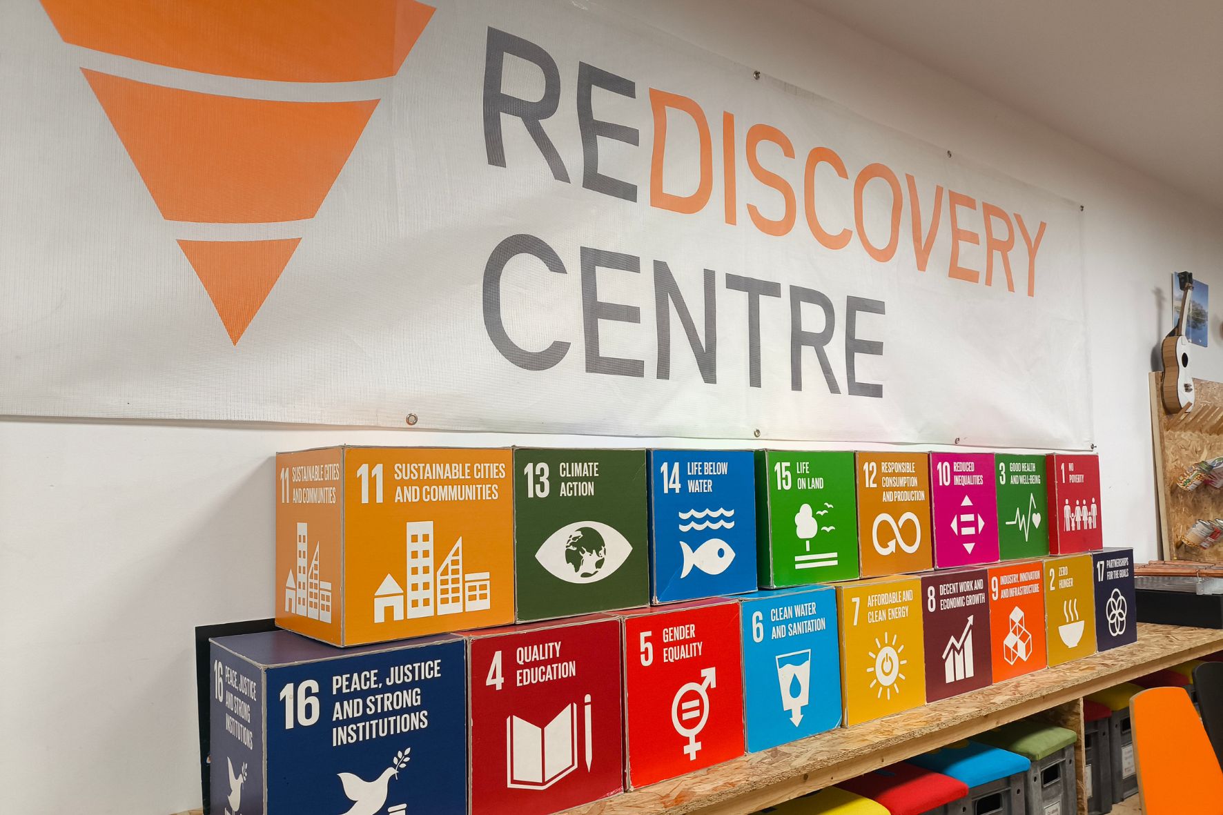 Bild zeigt die SDGs in Form von Blöcken auf einem Regal stehend, dahinter der Schriftzug "Rediscovery Center".