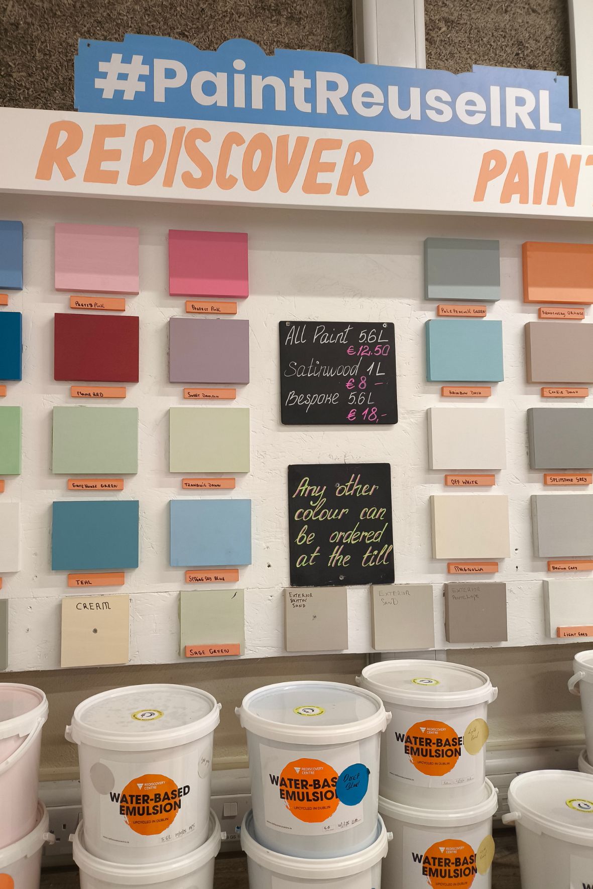 Bild zeigt Tafeln mit verschiedenen Farben an einer Wand, davor stehen Farbkübel. Überschrift: Redicover Paint.