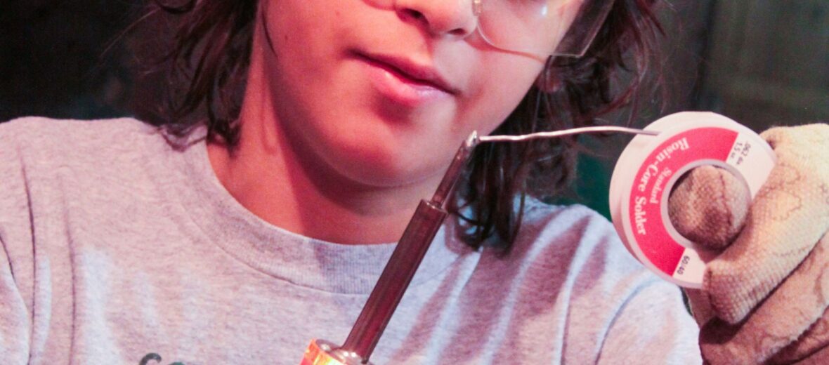 Das Bild zeigt einen Jungen mit Lötkolben und Lötdraht in der Hand. (c) Alla Kemelmakher auf Unsplash