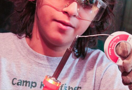 Das Bild zeigt einen Jungen mit Lötkolben und Lötdraht in der Hand. (c) Alla Kemelmakher auf Unsplash