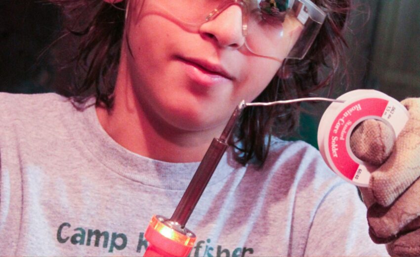 Das Bild zeigt einen Jungen mit Lötkolben und Lötdraht in der Hand. (c) Alla Kemelmakher auf Unsplash