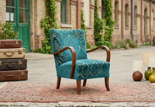 Das Bild zeigt mehrere Vintage-Artikel, links im Bild mehrere alte Koffer, in der Mitte einen türkisen Stuhl und rechts mehrere Lampen.