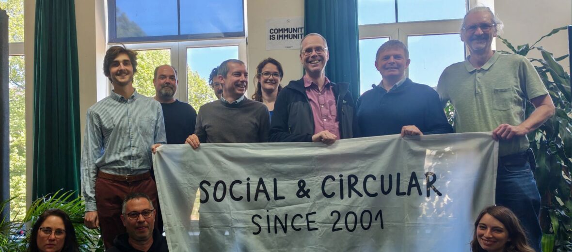 Bild zeigt mehrere Teilnehmer:innen beim RREUSE Netzwerktreffen in Brüssel 2026; Sie halten ein Plakat mit der AUfschrift: Social & Circular since 2001 (c) RREUSE