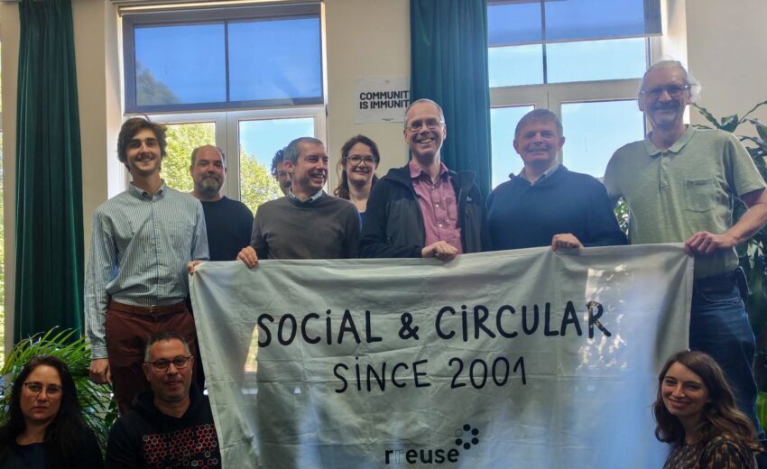 Bild zeigt mehrere Teilnehmer:innen beim RREUSE Netzwerktreffen in Brüssel 2026; Sie halten ein Plakat mit der AUfschrift: Social & Circular since 2001 (c) RREUSE