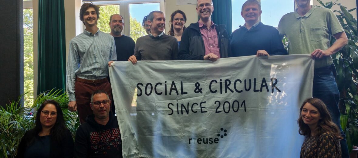 Bild zeigt mehrere Teilnehmer:innen beim RREUSE Netzwerktreffen in Brüssel 2026; Sie halten ein Plakat mit der AUfschrift: Social & Circular since 2001 (c) RREUSE