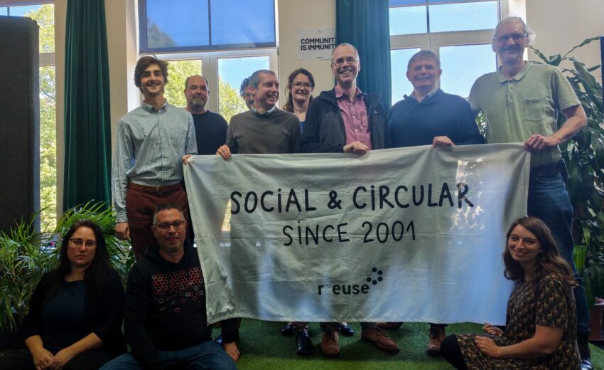 Bild zeigt mehrere Teilnehmer:innen beim RREUSE Netzwerktreffen in Brüssel 2026; Sie halten ein Plakat mit der AUfschrift: Social & Circular since 2001 (c) RREUSE
