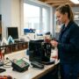 Bild zeigt eine Frau in einer Werkstatt beim Reparieren einer Kaffeemaschine.